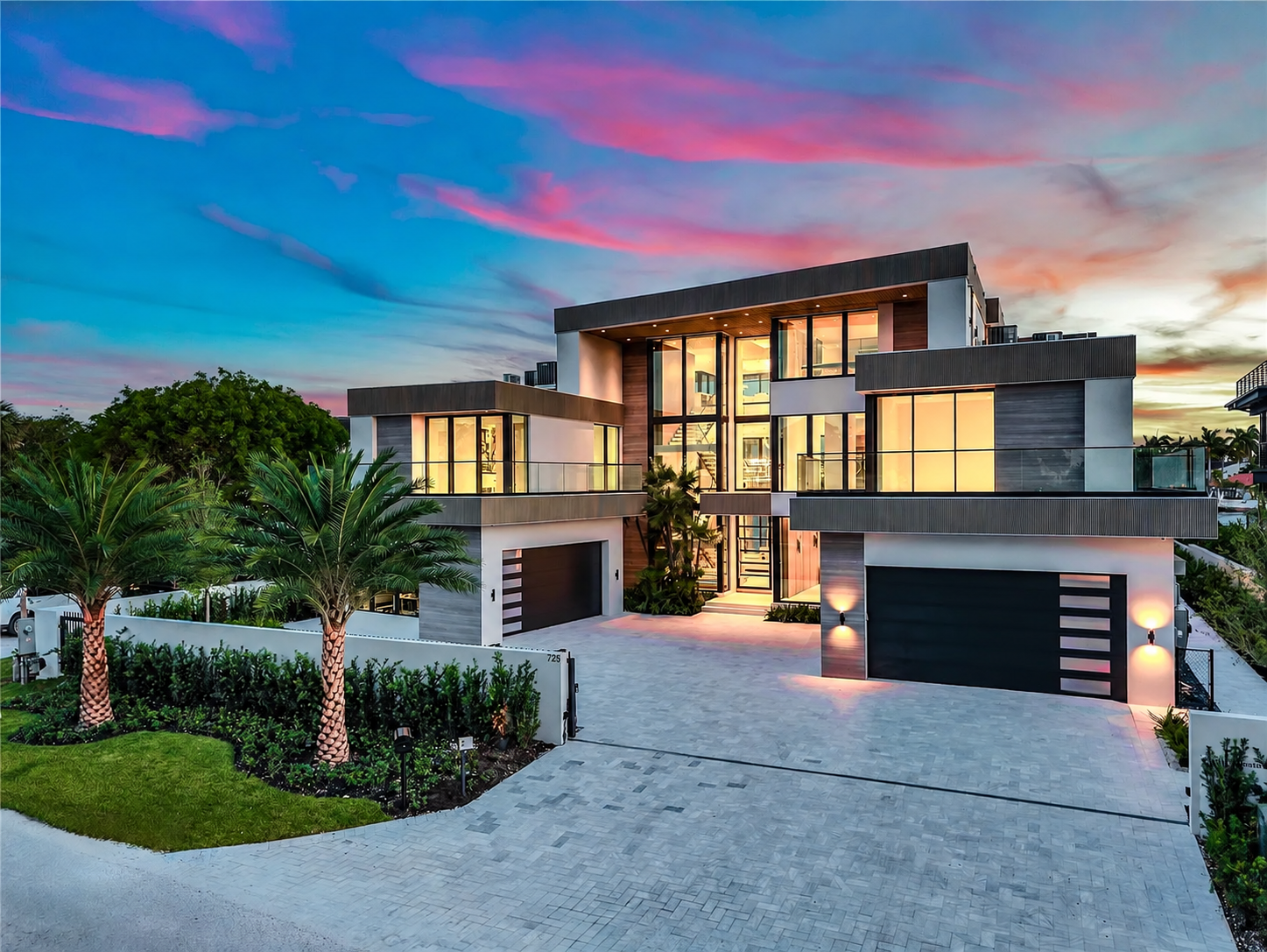 Twilight view of the residence entrance with palm trees