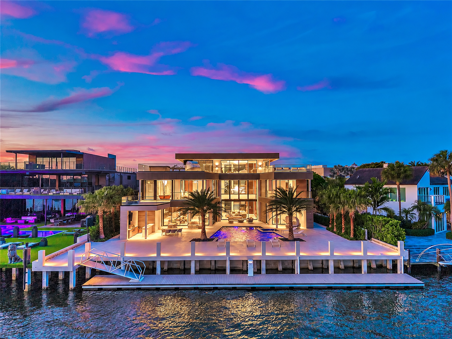 Waterfront elevation of the residence at dusk with pool and dock